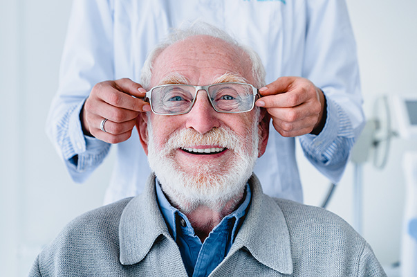 Senior patient being fitted with glasses, smiling.