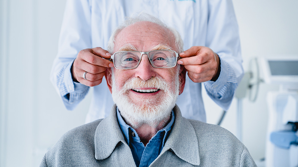 Senior patient being fitted with glasses, smiling.